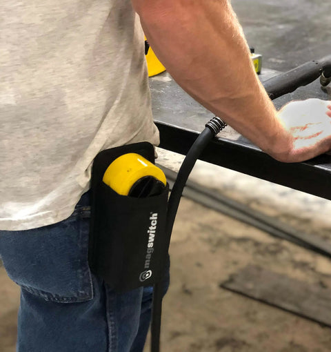 Hella Strong Mini Adjustable Welding Magnet With Slick On Off Rotating Base And 150 Lb Hold Power For Multi Angle Metal Fabrication secured in a holster on a worker's waist.
