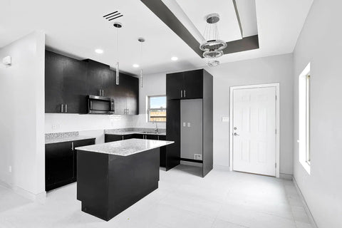 Modern kitchen with black cabinets, white countertops, and geometric ceiling design in an open space, featuring sleek decor.