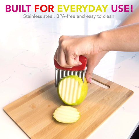 Joie crinkle cutter knife with red handle and stainless steel wavy blade slicing a green apple on a cutting board.
