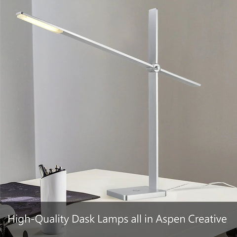Modern silver desk lamp with adjustable arm on office desk, surrounded by stationery and computer equipment