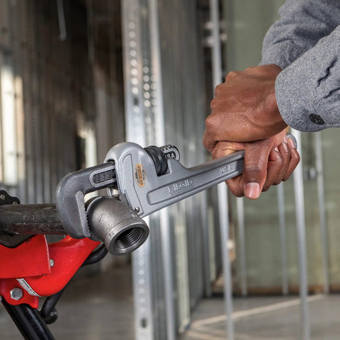 Person using Pro Grade Aluminum 12 Inch Straight Pipe Wrench on a metal pipe, showcasing lightweight I-beam handle, silver finish.