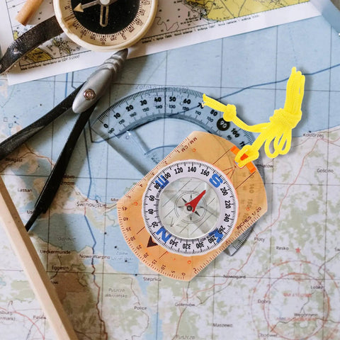 Orange Survival Compass With Lanyard For Hiking And Camping on a map, ideal navigation tool for backpacking and outdoor adventures.