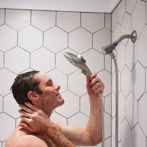 Person holding Spot Resist Brushed Nickel Six Function Five And A Half Inch Handheld Showerhead With Magnetic Docking System And Quick Release Hose