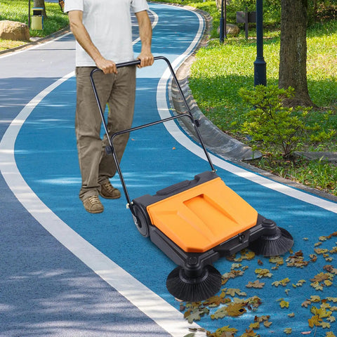 Heavy Duty 26 Inch Walk Behind Floor Sweeper With Foldable Handle cleaning leaves on a blue pathway, showcasing nylon brushes and easy maneuverability.
