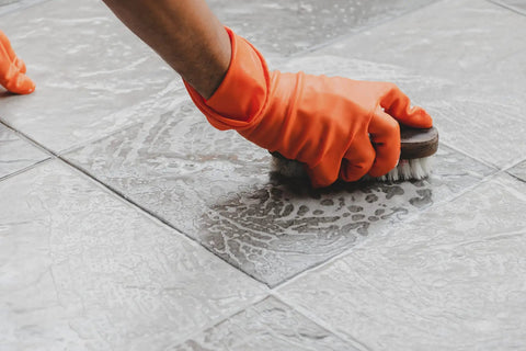 Person with orange gloves scrubbing tile floor with Heavy Duty All Surface Cleaner Concentrated Industrial Blend Kicks Serious Grime Away Works Like A Charm On Concrete Metal And Tile Yields Up To Ten Gallons Rock Solid Safe For Everyday House Maintenance Without Harmful Fumes.