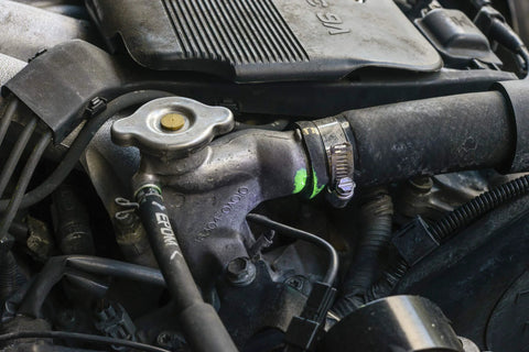 Automotive engine cooling system component: radiator hose, silver cap, and metal hose clamp