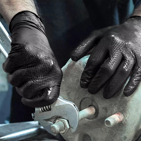 Close-up of black nitrile mechanic gloves with raised diamond texture gripping a wrench on a metal bolt