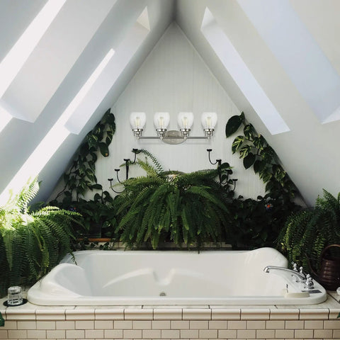 Belton Four Light Wall Bath Vanity Light Fixture With Brushed Nickel Finish, Clear Seeded Glass Shades above a bathtub in bright bathroom