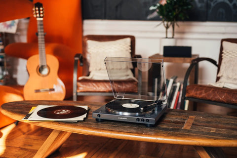 Front view of Audio-Technica at-LPGO-BT turntable, gun-metal/black with clear dust cover, playing vinyl on a coffee table