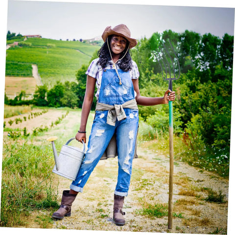 Farmer holding Beast Of A Grass Fork For Manure Handling And Garden Cleanup, standing on a farm path, smiling, with watering can