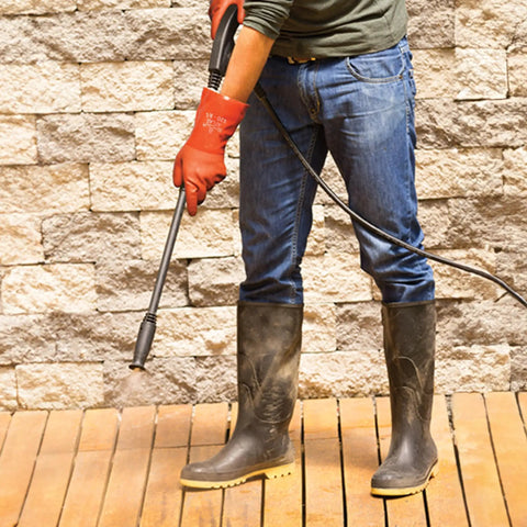 Person using high-pressure washer wearing Atlas 620 Double-Dipped PVC Chemical Resistant Gloves With Rough Grip, Size Small, Orange, 12 Pack