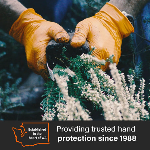 Gloveworks orange nitrile work gloves with raised diamond grip; close-up of hands gripping plant stems.