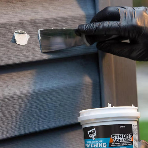 Application of Weatherproof Patching Compound 16oz White For Drywall And Masonry Repairs on wood siding with a putty knife