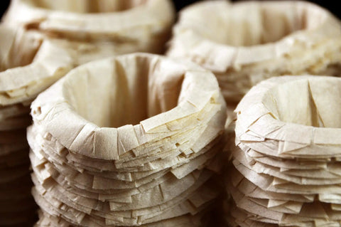 Stacks of unbleached disposable K-Cup paper filters for Keurig, compatible with Ekobrew EZ-Cup, showing texture detail.