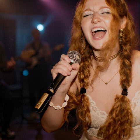 Singer using Spark Link XLR Wireless System For Dynamic Microphones Pro Grade Studio Audio on stage, close-up view.