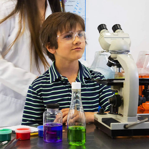 Boy wearing Kickass Kids Safety Glasses Featuring Hella Clarity Impact Resistant Polycarbonate Lenses in school lab setting.