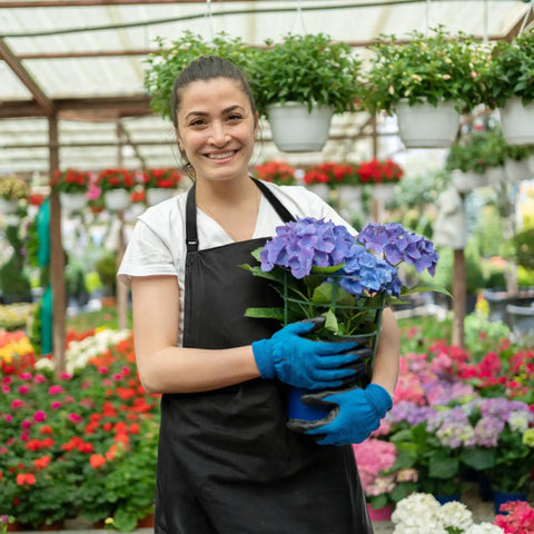 Person wearing extra long waterproof vinyl apron with adjustable neck strap and long waist ties, holding flowers in greenhouse.