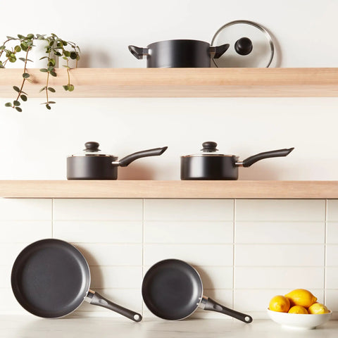 Hassle Free Ceramic Nonstick Eight Piece Pots And Pans Set With Cool Grip Soft Handles arranged on wooden shelves in black finish.
