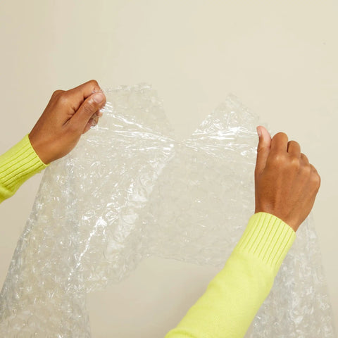 Hands holding heavy duty bubble cushioning wrap, demonstrating its use for fragile gear. Kick Your Packing Game Up A Notch With This Heavy Duty Bubble Cushioning Wrap Perfect For Shipping Storage Or Moving Clear Perforated Rolls That Keep Fragile Gear Secure.