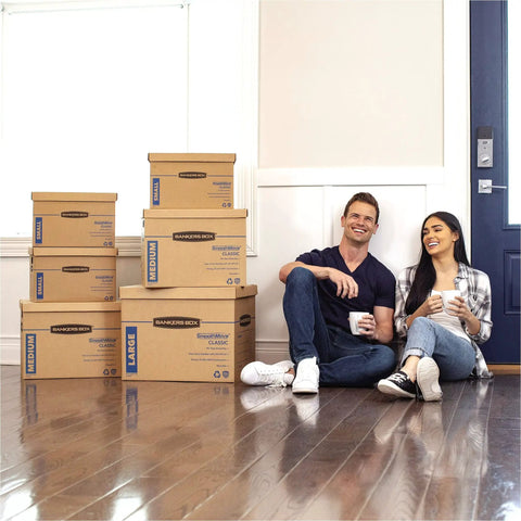 Solid Gear Medium Moving Boxes 20 Pack With Tapeless Assembly And Reinforced Carry Handles, stacked boxes next to a happy couple on wooden floor.