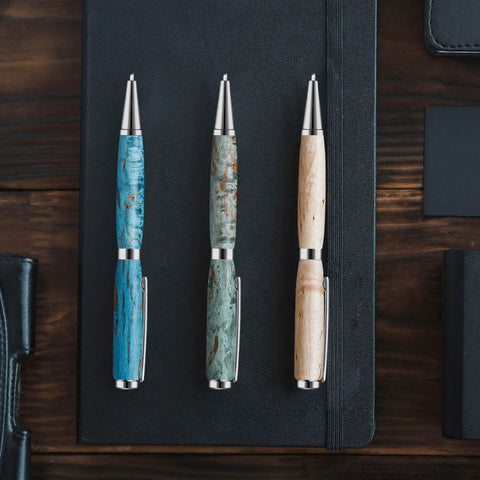 Knockout Twenty Piece 7Mm Slimline Twist Pen Kit With Shiny Silver Refills; three custom pens with silver accents on a black notebook.
