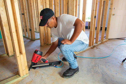Person using nailer with 21 Degree Plastic Strip Round Head Framing Nails Bright Coated 3 In By 0.120 In Collated For 21 Degree Systems