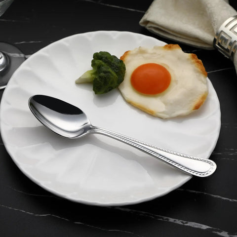 Top Tier Stainless Steel Dinner Spoons With Pearled Edge Handles Solid Balance Build Dishwasher Safe And Slick Silver Polish on a plate with egg and broccoli.