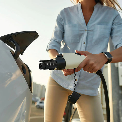 Person using NACS To J1772 EV Charger Adapter For Level 1 And Level 2 Charging, 80 Amps At 250 Volts on electric vehicle.