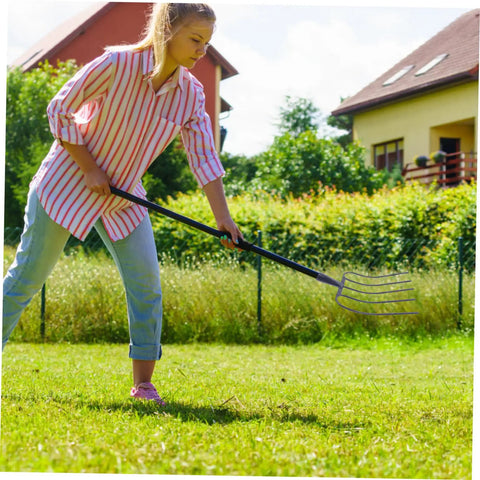 Person using Five Pronged Iron Manure Fork For Farming And Gardening, Heavy Duty Rake For Quick Lawn Cleanup And Manure Removal.