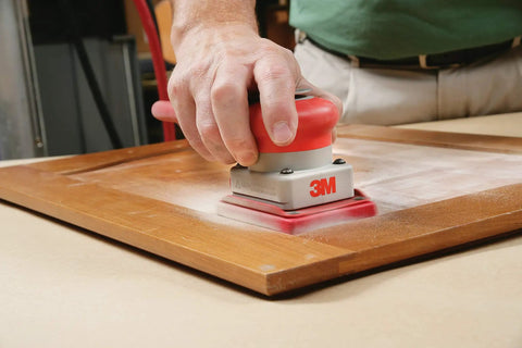 Hand using sander on wood surface with Aluminum Oxide Utility Cloth Sheets 11 Inch By 9 Inch 240 Grit Pack Of 50 for smoothing.