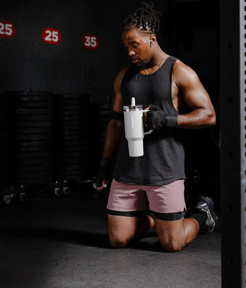 Solid Double Wall Vacuum Insulated Flip Straw Travel Tumbler With Secure Leakproof Lid Keeps Drinks Ice Cold All Day Long Rose Quartz Thirty Ounce portable cup held by a fit person during gym workout.