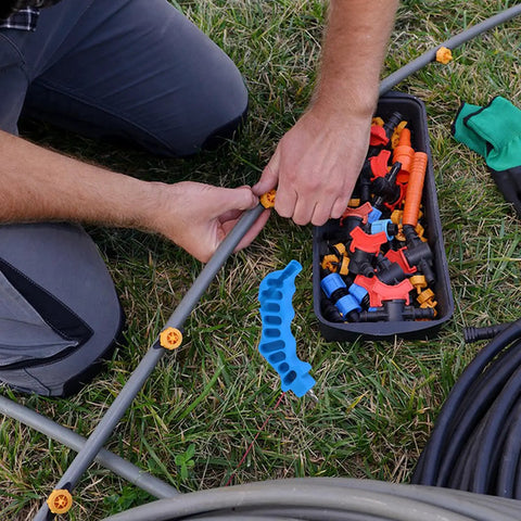 Close-up of hands using 2 In 1 Drip Irrigation Hole Punch And Fitting Insertion Tool Kit For One Quarter Inch PE Tubing on grass