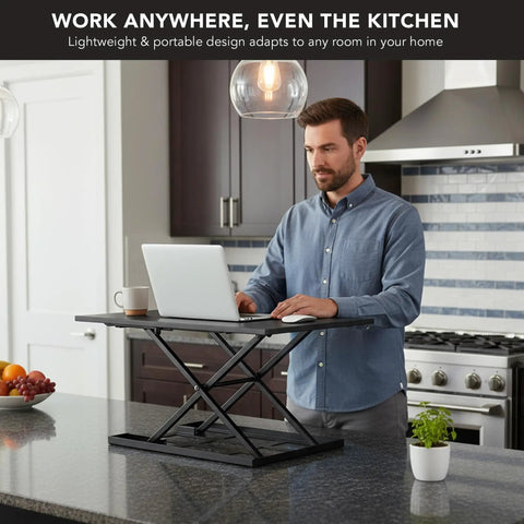 Man using 32 By 22 Inch Standing Desk Converter With Gas Spring Lift Slim Two And A Half Inch Low Profile Sit Stand Desk Riser in kitchen