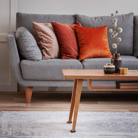 Modern living room with gray sofa, colorful cushions, wooden coffee table, and decorative vase on carpeted floor.