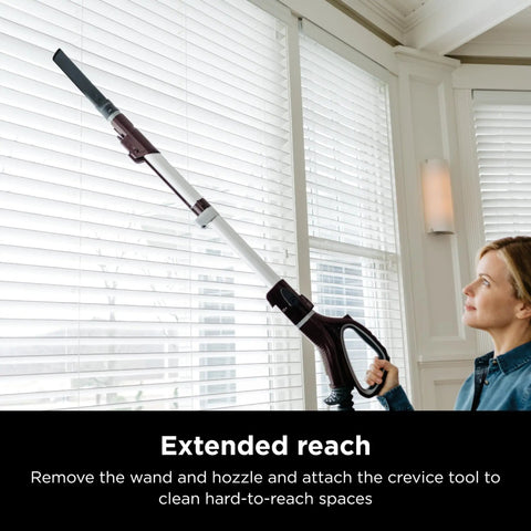 Woman using the crevice tool attachment on Shark Rotator Powered Lift Away TruePet Upright Vacuum With Hepa Filter for blinds.