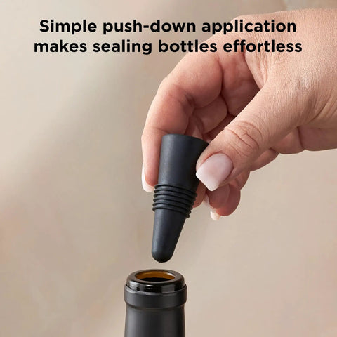 Preserve Your Opened Bottles With This Game Changing Set Of Four Multicolor Wine Stoppers, one being placed on a bottle.