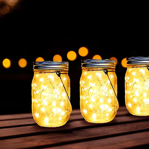 Solar Mason Jar Lid Lights 12 Pack With 30 LEDs For Outdoor Use Fairy In A Jar Style String Lights glowing on wooden table