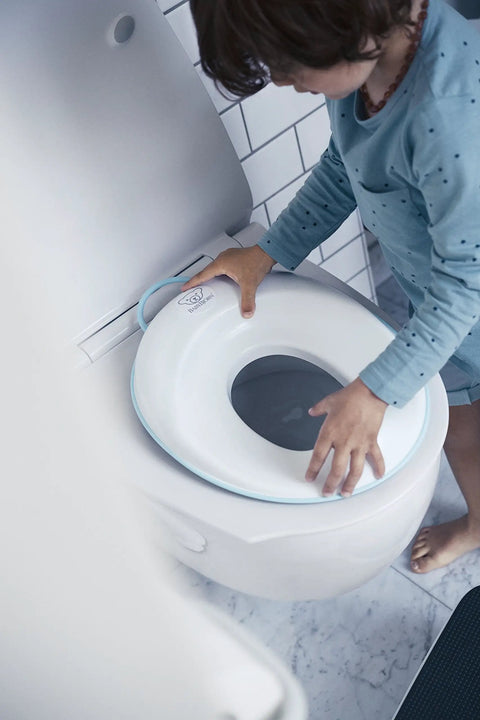 Child using Hassle Free Potty Training Seat With Built In Splash Guard Adjustable Toilet Adapter on white toilet.