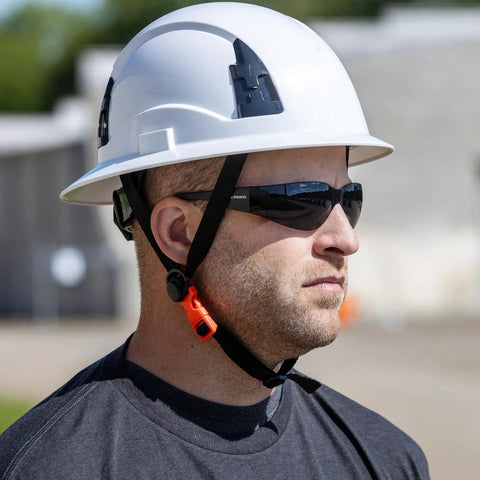 Worker wearing tinted safety glasses from 12 pack ANSI Z87 Plus UV Eye Protection for construction, outdoor work, industrial safety.