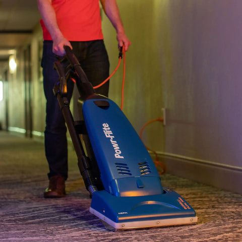 Person using Powr-Flite Borelli Dual Pro Upright Vacuum With HEPA Filtration for carpet cleaning in a hallway.