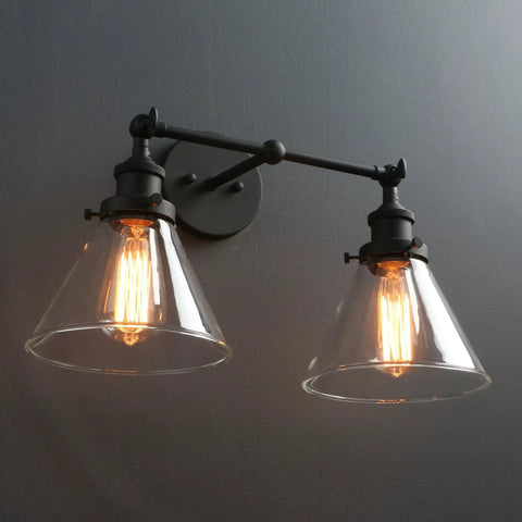Two Light Industrial Wall Sconce in Antique Black with 7.3 Inch Cone Clear Glass Shade illuminating a dark wall