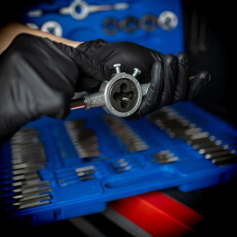 Hands using Beast 110 Piece Metric Tap And Die Set For Threading Bolts And Pipes, focus on die tool with blue case background.
