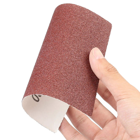 Hand holding a sheet from the Quarter Sheet Sandpaper Set With 50 Assorted Grits For Palm Sander 5.5 By 4.5 Inches Car And Wood Sanding Papers 60 80 120 180 240 320 400 600 800 1000 Grit Ideal For Auto Bodywork And Woodworking Finishing All In One DIY Friendly Kit