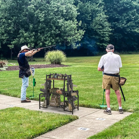 Built Like A Tank Vertical Floor Gun Rack Stores Eight Long Guns And Six Pistols With Rust Resistant Steel Frame set up in shooting range, featuring rifles and pistols.