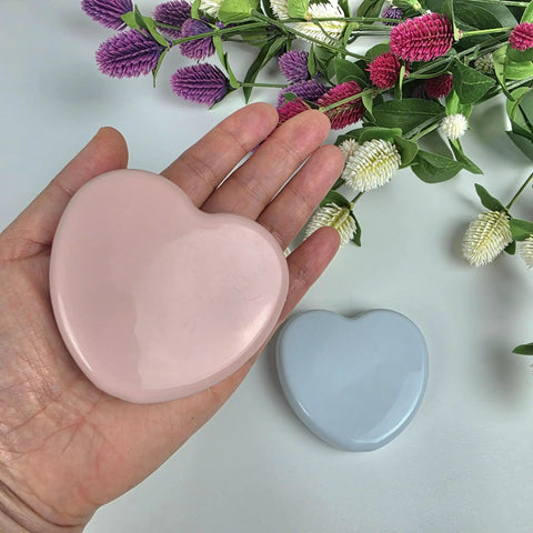 Compact Travel Sewing Kit Two Pack Featuring Adorable Heart Shaped Cases Pink And Blue held in hand with flowers in background.