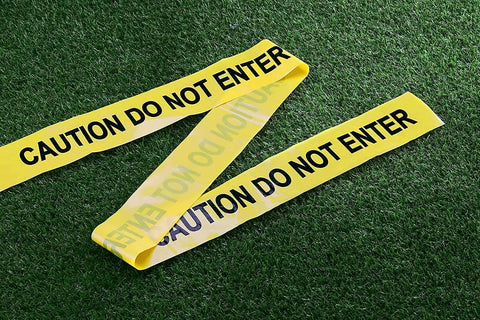 Heavy Duty Yellow And Black Caution Barricade Tape For Job Sites and Crew Patrols Non Adhesive Plastic Warning Roll on grass.
