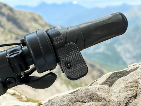 E-bike handlebar with Universal Thumb Throttle Adapter for E Bikes Converts Twist To Thumb Control With A Big Paddle installed