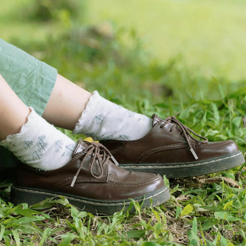 Upgrade Your Daily Drip With Top Tier Metal Alloy Shoe Lace Tips Built To Outlast Worn Aglets on brown shoes in grass.
