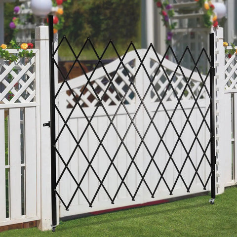 Badass Wall Mounted Folding Security Gate Smooth Glide Expanding Accordion Barricade in black, mounted near a white fence.