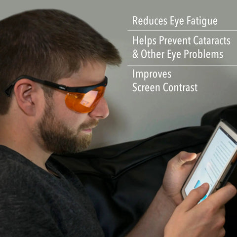 Man wearing blue light blocking computer glasses with SCT orange lens using a tablet, promoting eye strain relief and comfort.